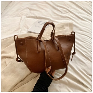 Détail du sac cabas en cuir marron grainé avec coutures précises et structure latérale
