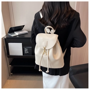 Close-up of a cream PU leather backpack with a gold metal hook and drawstring closure