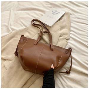 Détail d'un sac cabas en cuir litchi caramel avec surpiqûres blanches contrastées