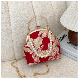 Detail of red vintage evening bag with golden floral embroidery and pearl handle strap