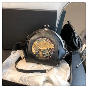 Close-up of vintage black leather shell bag with gold elephant relief in gift box