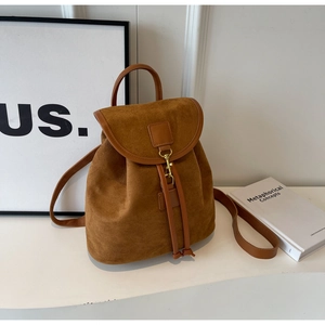 Detailed shot of brown suede minimalist backpack with gold metal hook closure and drawstring