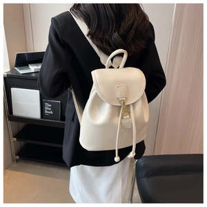 Detail of cream white leather backpack showing drawstring closure and gold metal buckle