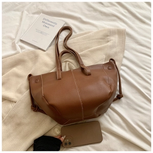 Détail macro d'un sac cabas en cuir grainé marron avec surpiqûres blanches contrastées