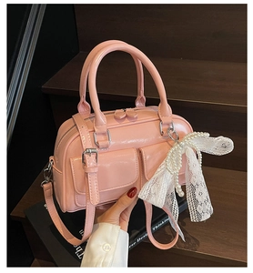 Detail of pink patent leather pillow bag with pearl lace bow and dual flap pockets