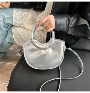 Détail d'un sac demi-lune argenté avec poignée métallique et texture cuir brillant