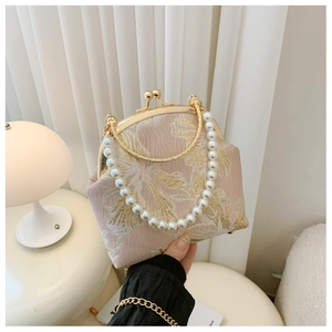 Detailed shot of vintage pink jacquard clutch with pearl handle and golden chain strap