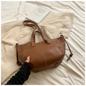 Sac cabas marron en cuir grainé avec surpiqûres blanches sur literie douce