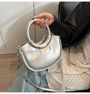 Gros plan du sac demi-lune argenté avec poignée ronde et détails plissés