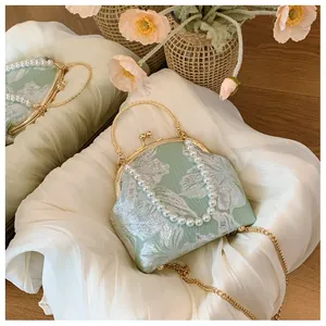 Detail of mint green floral jacquard evening bag with pearl handle and golden frame