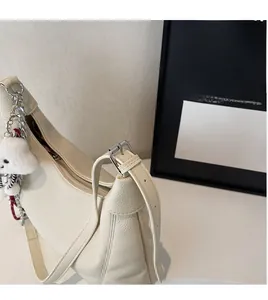 Detail of cream lychee leather tote bag with silver buckle and cute plush puppy charm