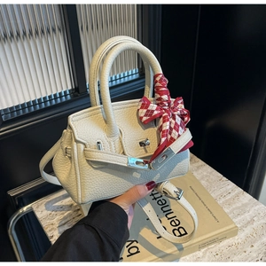 Detail der cremeweißen Mini-Handtasche aus Leder mit Seidenschal am oberen Griff