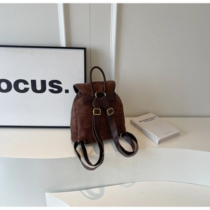 Detail of a vintage dark brown matte backpack with gold hardware and flap closure