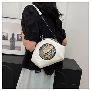 Detail of white lychee leather shell bag featuring vintage metal elephant relief and chain