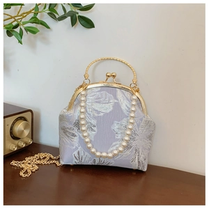 Detail of lilac brocade handbag with silver floral patterns and pearl bead handle