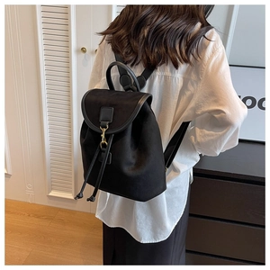 Détail d'un sac à dos noir mat avec cordon de serrage et boucle en métal doré
