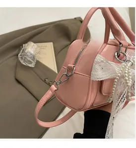 Close-up of pink Boston bag showing silver hardware, lace bow and pearl charms