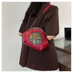 Detail of red shell bag featuring vintage metal elephant relief and chain shoulder strap