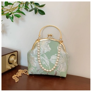 Detail of light green floral brocade bag with pearl chain and golden metal handle