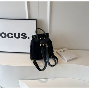 Detail of minimalist black matte backpack with elegant gold buckles on a white display