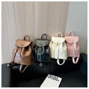 Row of four colorful leather backpacks with gold metal buckles on a black leather sofa