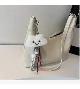 Detail of off-white hobo bag with lychee texture and plush cloud charm accessory