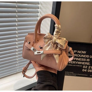 Detail einer rosa Handtasche aus Leder mit einem Seidentuch um den Griff gewickelt