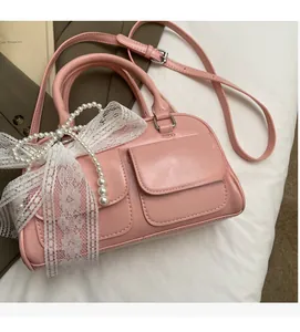Detail of pink Boston bag featuring decorative lace bow and pearl charm ornament