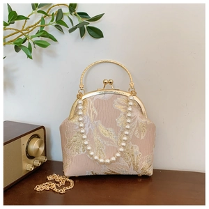 Detail of pink floral embroidery and pearl handle on a vintage shell clutch bag