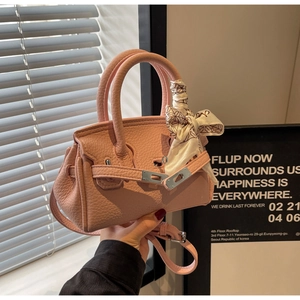 Detail einer rosa Handtasche aus Leder mit seidenumwickeltem Griff und Silberverschluss