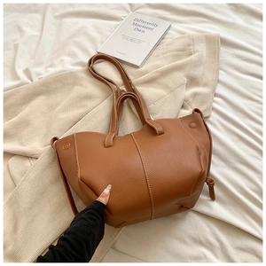 Détail du sac cabas marron avec motif litchi et nœud décoratif sur le côté