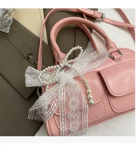 Detail of pink pillow bag with pearl string and lace bow on professional brown jacket