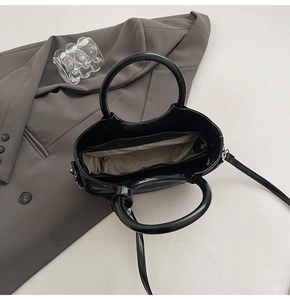 Vue de dessus de l'intérieur du sac en cuir verni noir avec compartiments et sangle