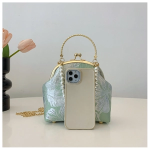 Close-up of vintage mint green satin handbag with floral brocade and pearl strap