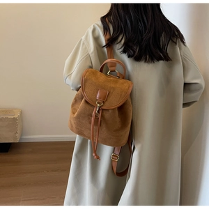 Detail view of brown suede backpack with drawstring closure and vintage metal buckles