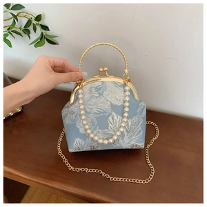 Detail of light blue floral jacquard bag with pearl handle and golden ring clasp