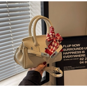 Detail der cremefarbenen Handtasche aus Kieselleder mit Metallschnalle und kariertem Seidenschal