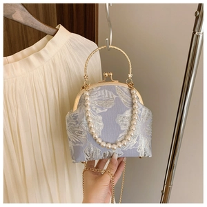 Detail of floral embossed handbag with gold metal handle and elegant pearl chain