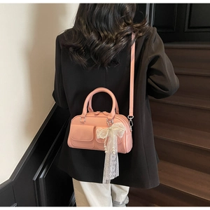 Pink patent leather bowling bag with lace pearl bow detail on a black blazer