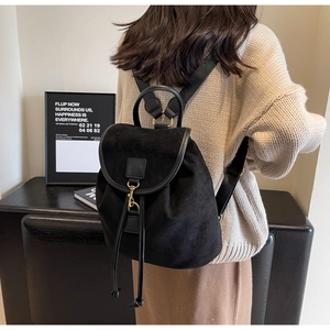 Close-up of black suede drawstring backpack with gold hardware and leather details