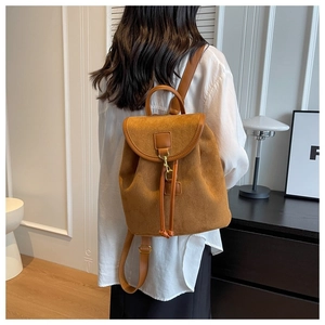 Détail du sac à dos en daim marron avec fermeture à cordon et crochet doré sur la sangle