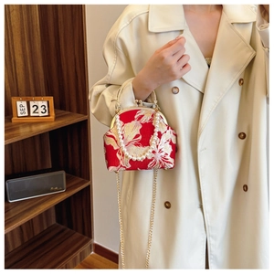 Close-up of red floral embroidery on qipao bag with pearl handle and gold chain