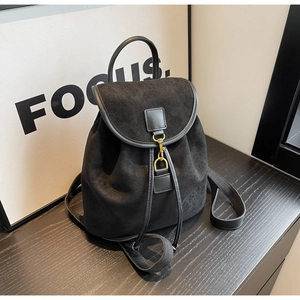 Detail of black suede backpack with gold metal hook buckle and drawstring closure