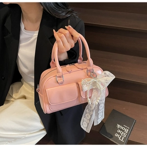 Close-up of pink Boston bag featuring lace bow, pearl chain and two front pockets