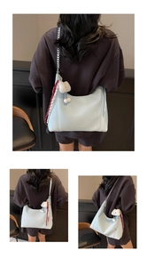 Detail view of light blue leather tote bag with silver chain strap and plush bear charm