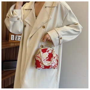 Detail of red silk embroidery handbag with pearl handle and golden floral patterns