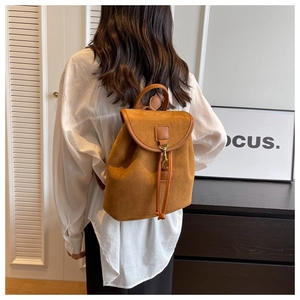 Vue détaillée d'une femme portant un sac à dos vintage en daim marron avec garniture