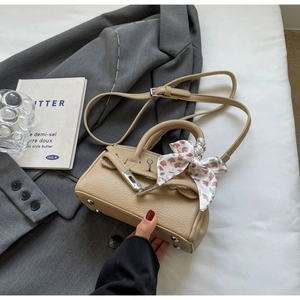 Detail der beigen Mini-Handtasche aus genarbtem Leder mit Seidenschal am Griff