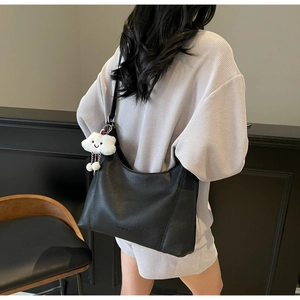 Macro shot of black pebbled leather hobo bag with a soft white plush cloud charm