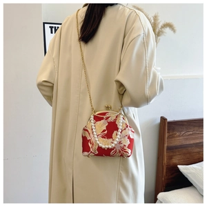 Detail of red cheongsam clutch with gold floral embroidery and pearl handle strap